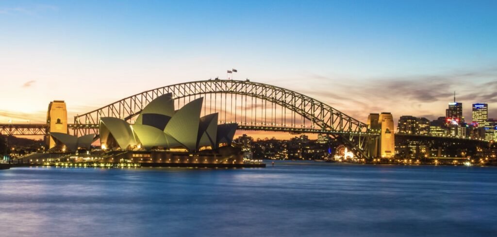 Sydney Opera House and Harbour Bridge at sunset, viewed from Mrs Macquarie’s Chair with warm golden light reflecting across Sydney Harbour.