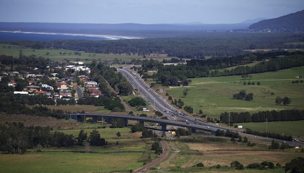 Aerial view of rolling green farmland in Gerringong, New South Wales, with bright grass fields stretching toward the horizon under clear daylight.